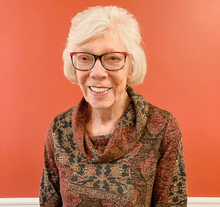 Photo of Lillian Miller Emmons standing inside in front of a wall.