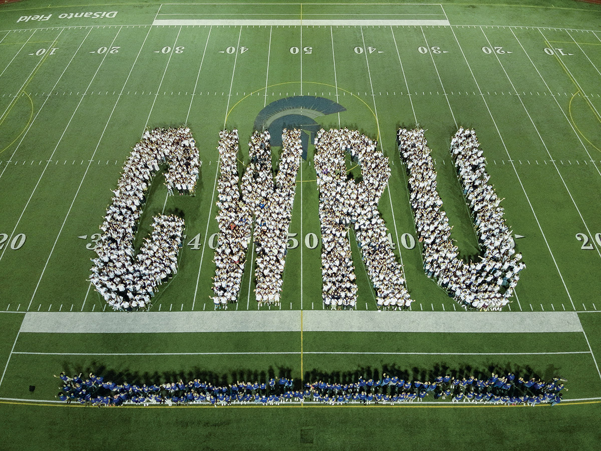 An image of Case Western Reserve's first-year students standing together on the university's football field and forming the letters of the university acronym: C W R U .