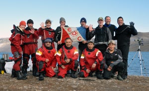 Martin Nweeia holding Explorers Flag with Inuit hunters and Fisheries and Oceans Canada team members in Pond Inlet.