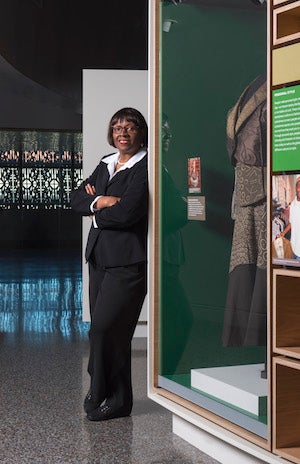 A portrait of Elaine Nichols standing near an exhibit at the Smithsonian’s National Musem of African American History and Culture