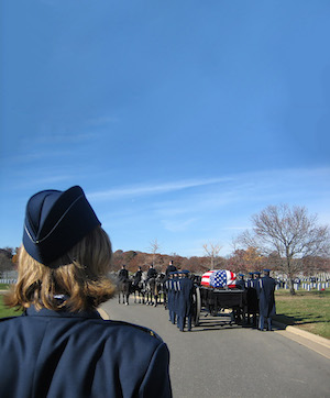 The back of the head of a woman, Sharon Bannister, in uniform, watching a military funeral