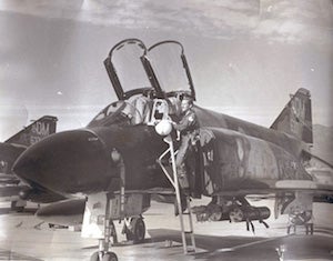 A black and white photo of an Air Force member, Stephen Rusch, next to a plane