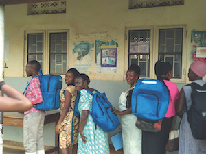 Several female Ugandan healthcare workers wearing blue backpacks designed by CWRU students