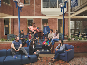 A group of Case Western Reserve students sitting on couches and chairs, smiling and laughing in the Thwing atrium.