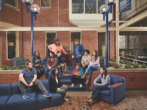 A group of Case Western Reserve students sitting on couches and chairs, smiling and laughing in the Thwing atrium.