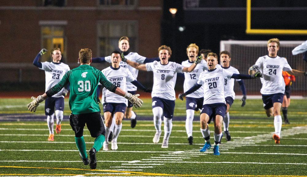 Case Western Reserve men's soccer players rush toward a teammate and goal keeper in celebration