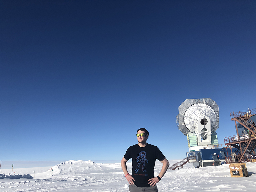 Allen Foster standing outside in the snow in front of a large telescope 