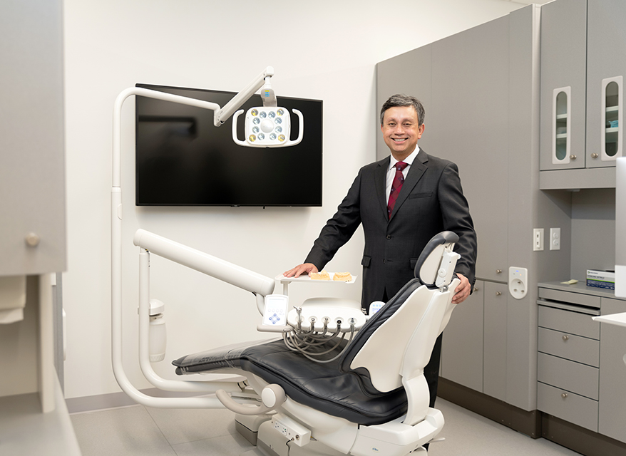Image of Andres Pinto standing behind a dental chair in an examination room