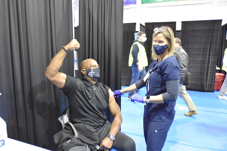 A man and nurse laugh together after the man receives his vaccine