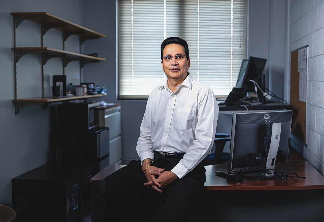 Photo of Vipin Chaudhary leaning against the edge of a deck in an office.