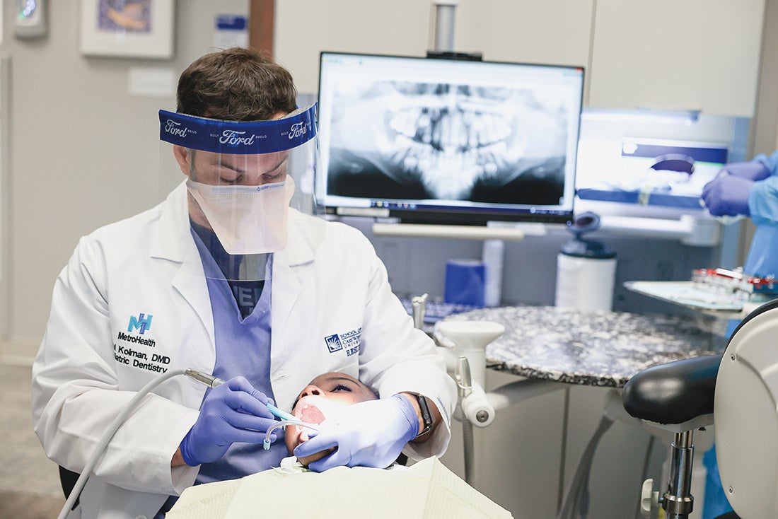 A dentist cleaning a woman’s teeth.