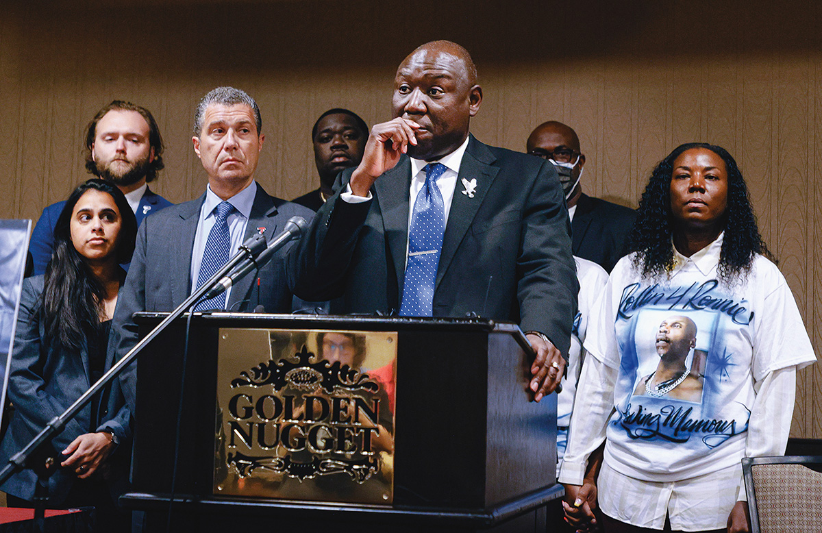 Ben Crump speaking at a podium with a group of attorneys and others, including members of George Floyd’s family, standing behind him.