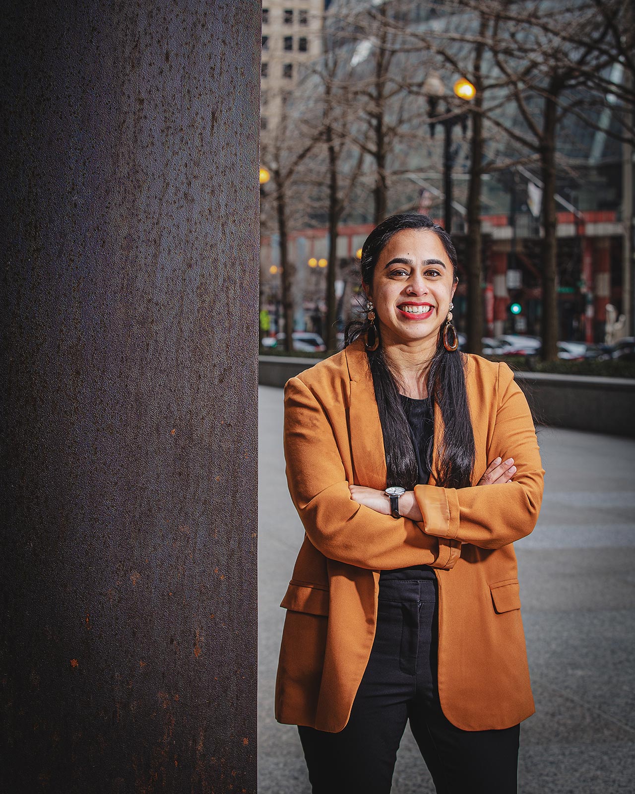 Raveendran standing with her arms crossed on the sidewalks of downtown Chicago