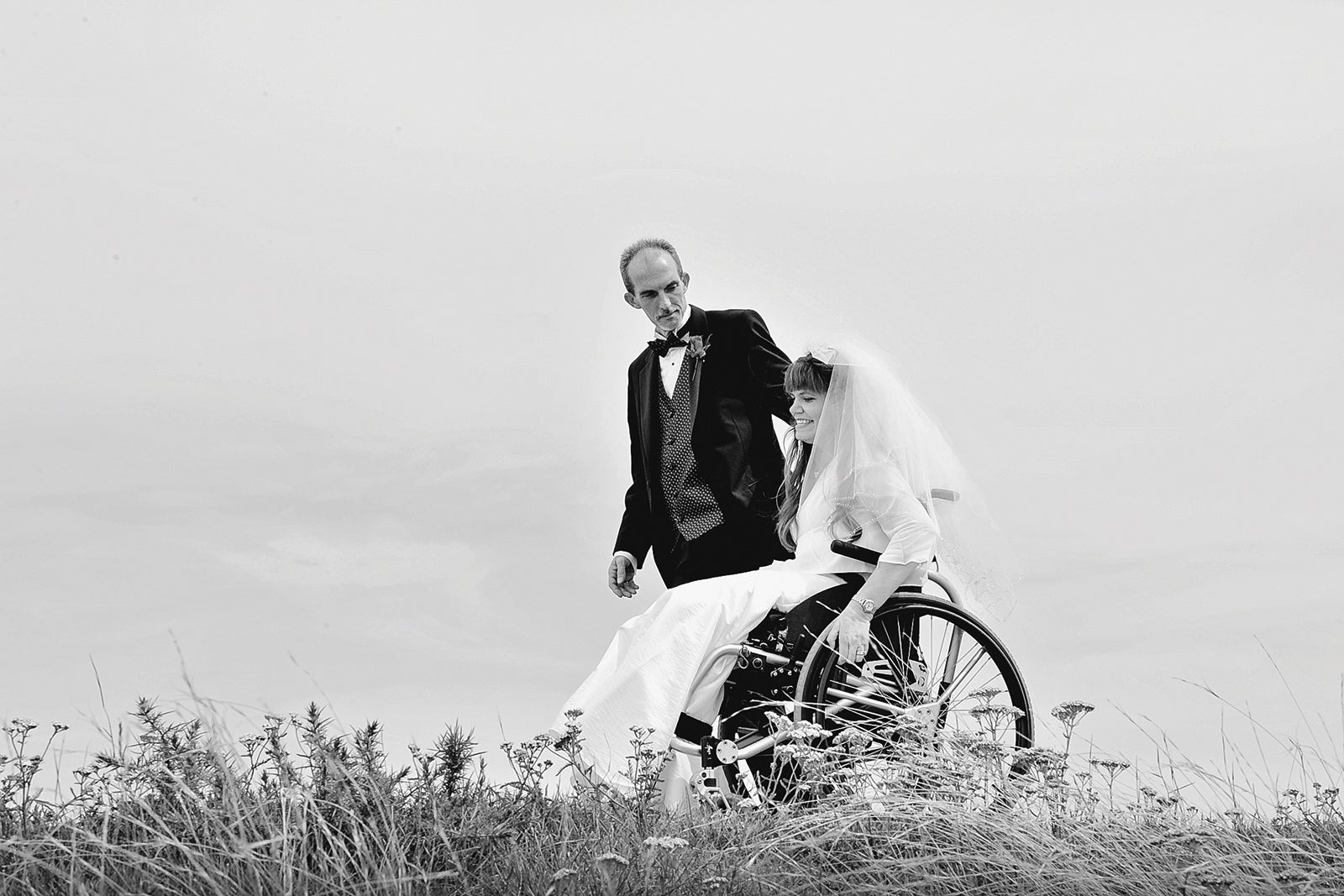 A black and white photo of Kim Anderson in her wedding gown next to her husband (in his tuxedo).