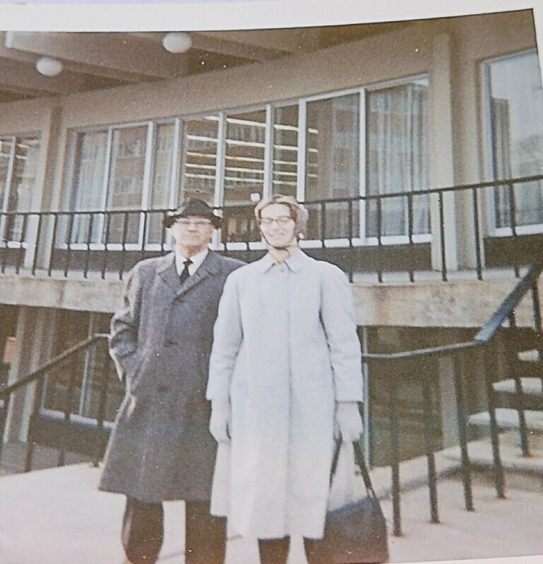 Two men in trench coats standing in front of a building