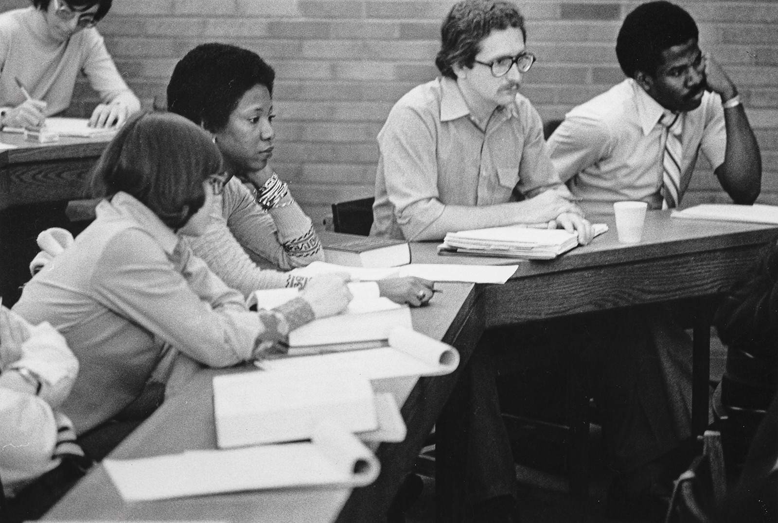 Five college students sitting in a classroom at desks.