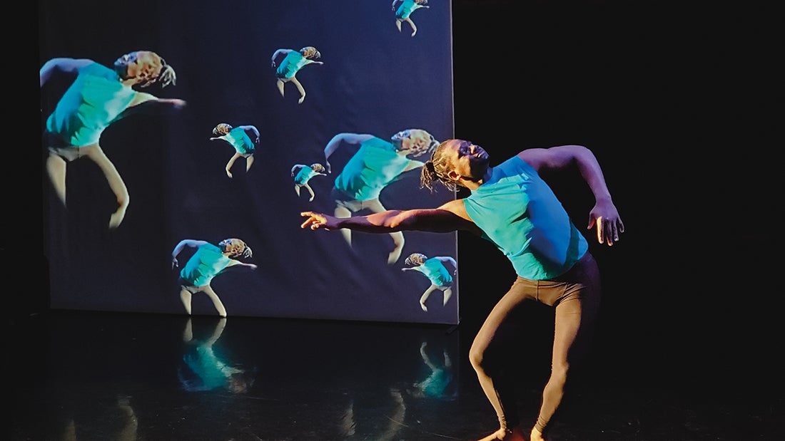 Shadrach Arthur dancing in front of live projections of himself on a screen.