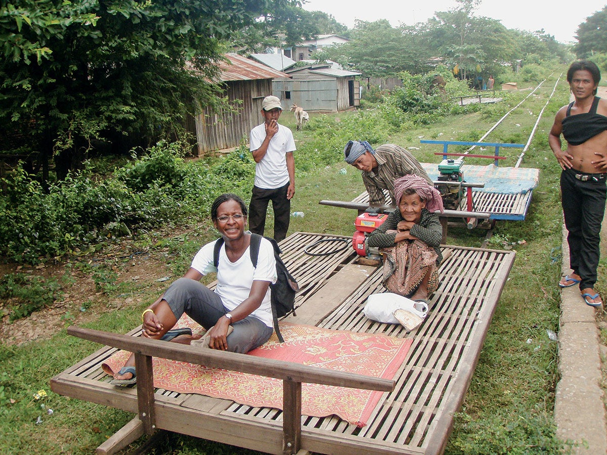 Darlene Grant sits on a Bamboo train with villagers in Cambodia