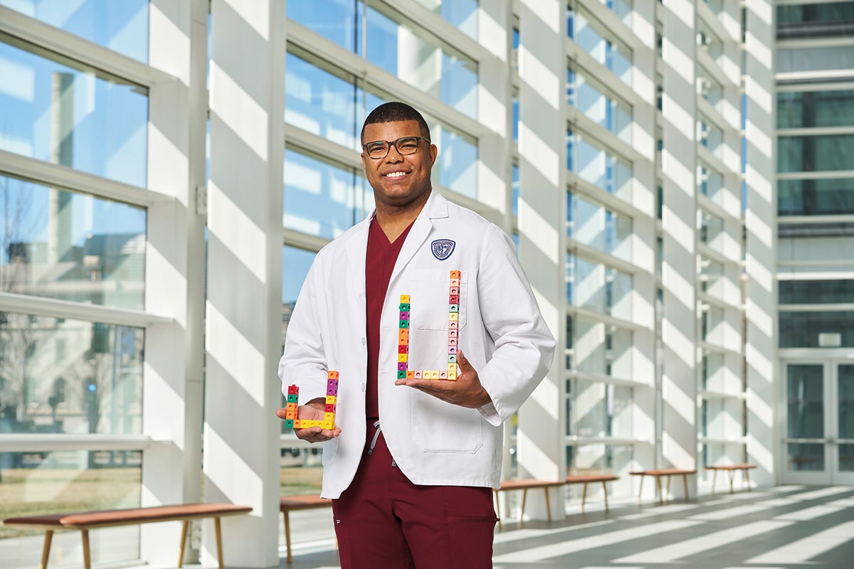 Medical student Brock Montgomery in a white coat holding cubes used to explain mathematical concepts
