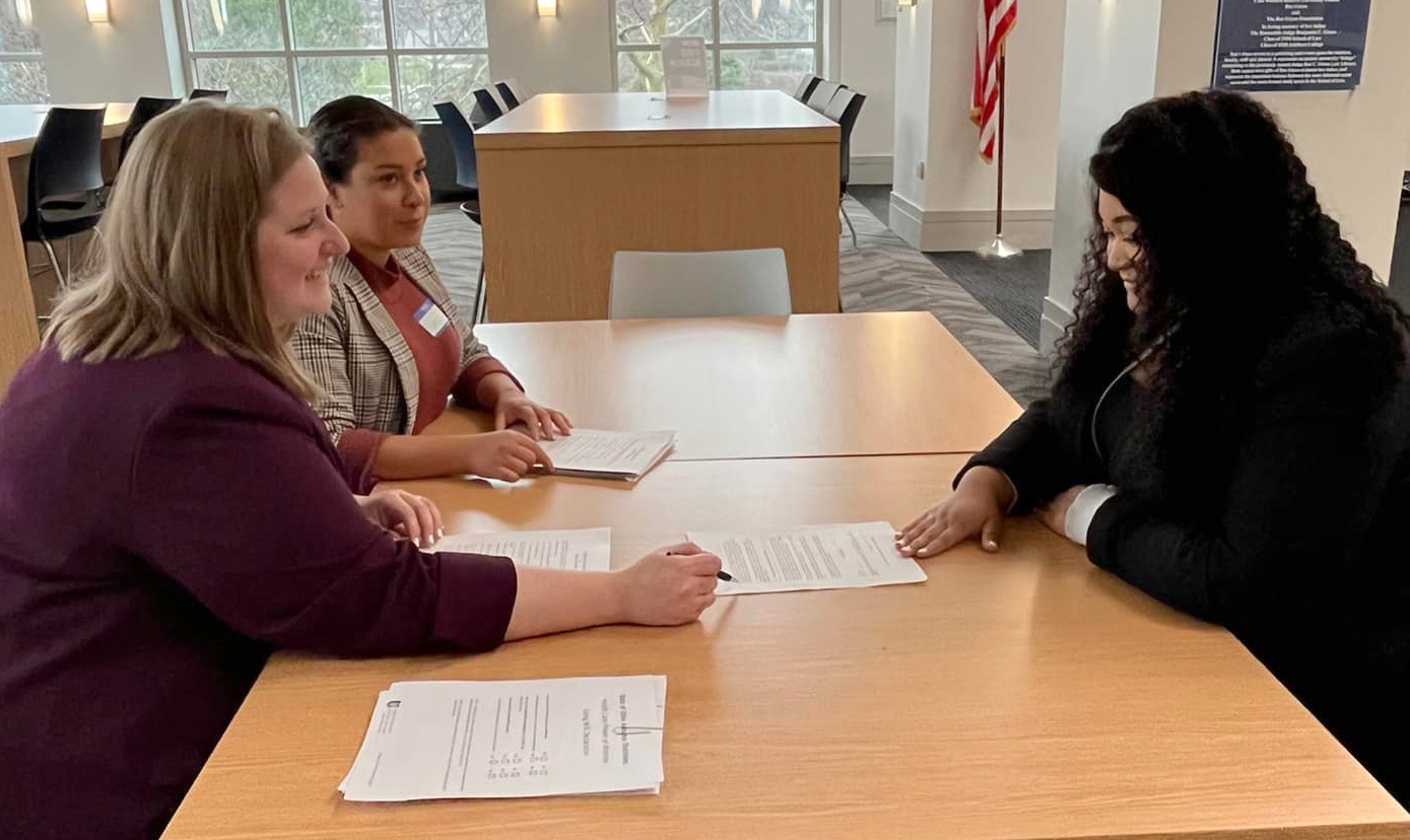 Photo of two law students at a table meeting with a client.