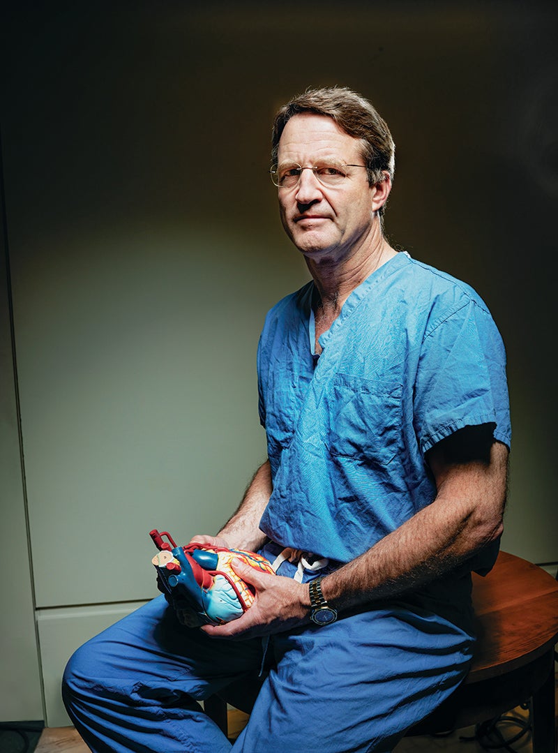 Photo portrait of surgeon, Craig Smith, seated and holding a heart model