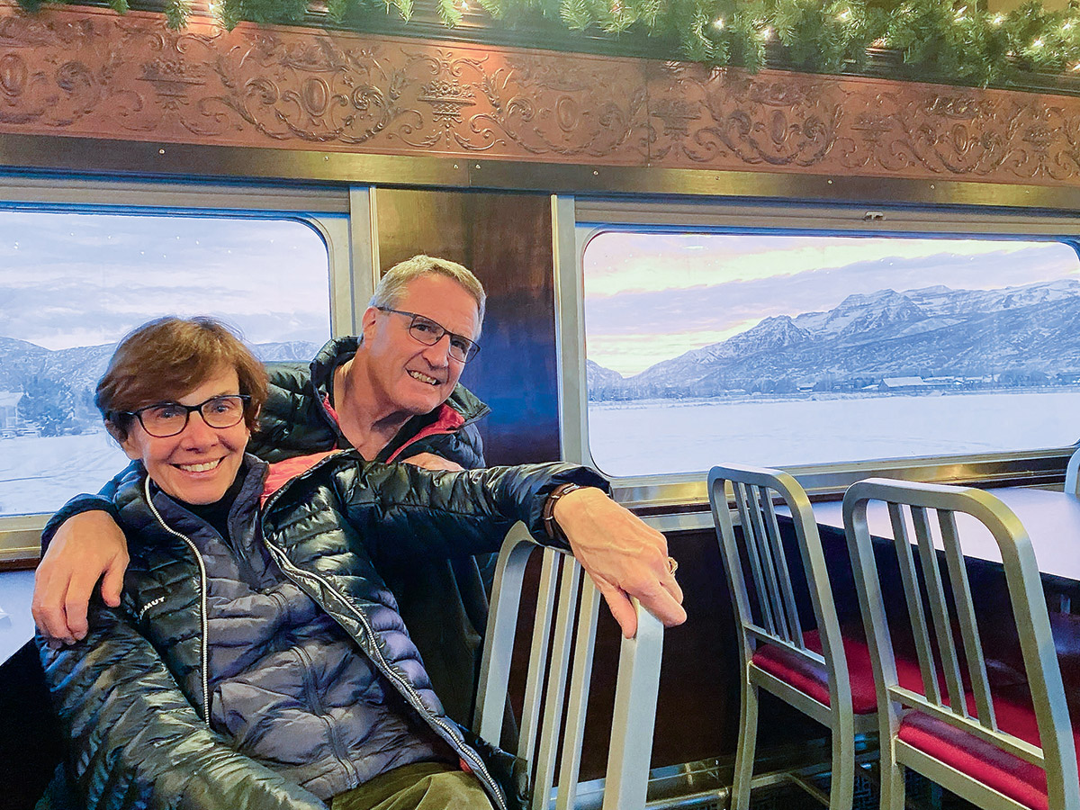 A photo of Trish and Craig Smith on a train with a Utah landscape seen outside the window.