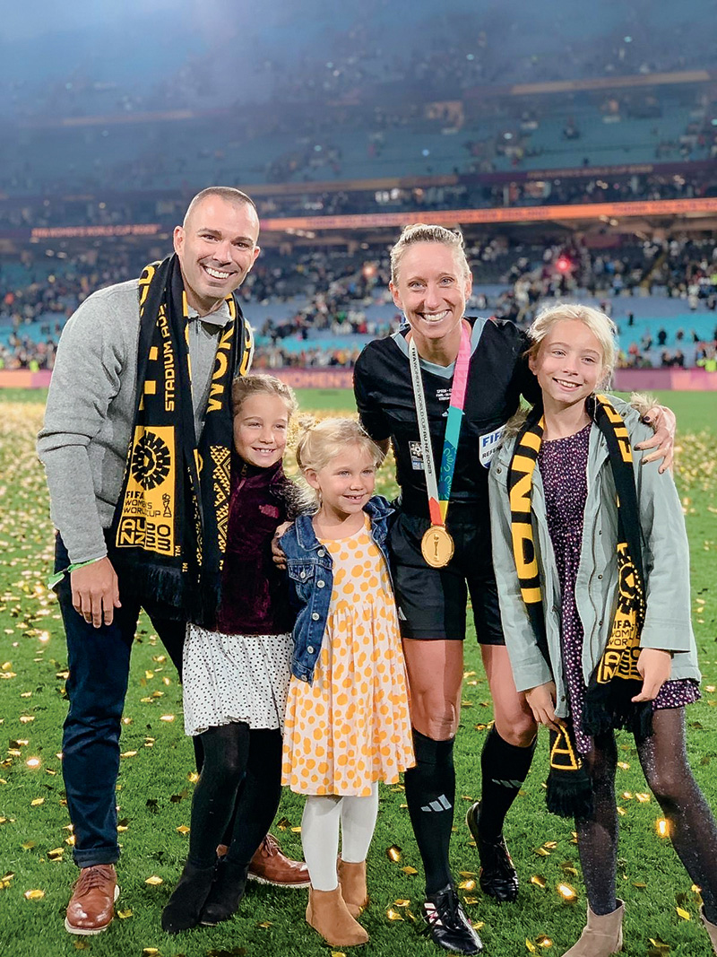A picture of two parents and their three children on a soccer field after the game.