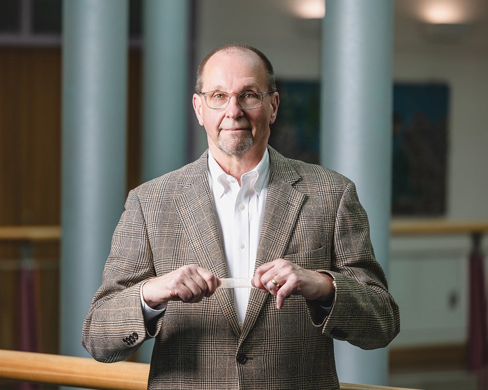 Gary Wnek standing and stretching a rectangular piece of multilayered rubbery polymers in his hands.