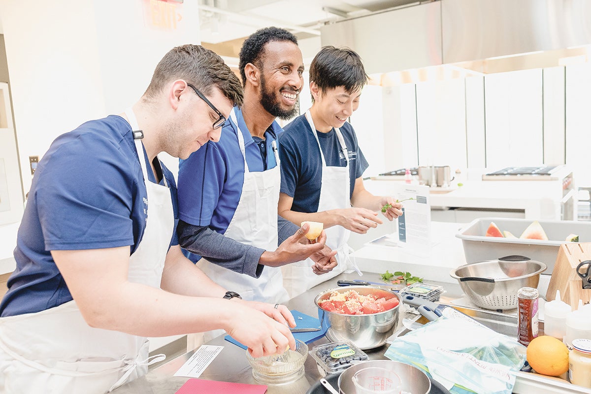 Three med students preparing a meal a station in the teaching kitchen