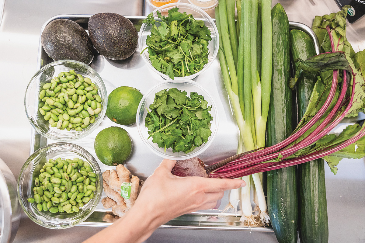Tray with avocados, beets, cucumbers, scallions, cilantro, parsley, ginger, and beans