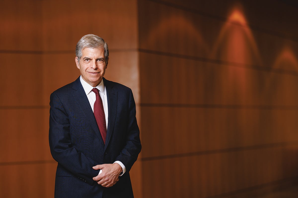A photo portrait of Gary Schwartz in suit and tie, standing with his hands clasped