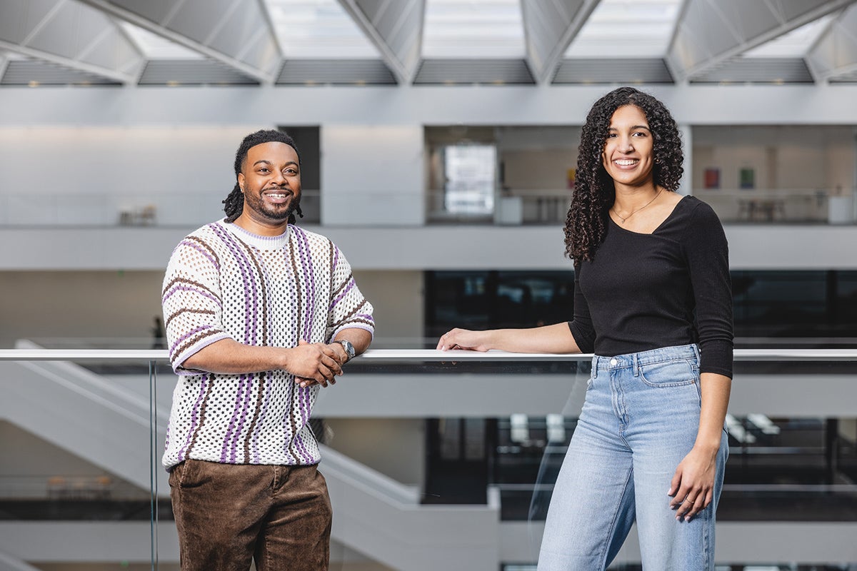 Indoor image depicting two students leaning against a railing.