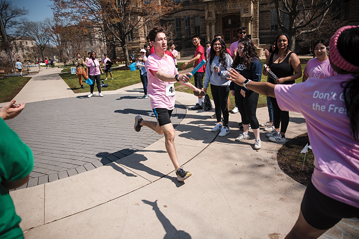 Student participating in Hudson Relays passing the baton to the next runner