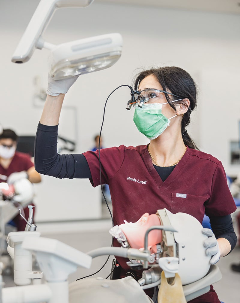 Female dental student works with a manikin