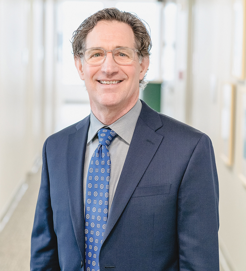 Photo of David Gerdes standing, smiling in a hallway