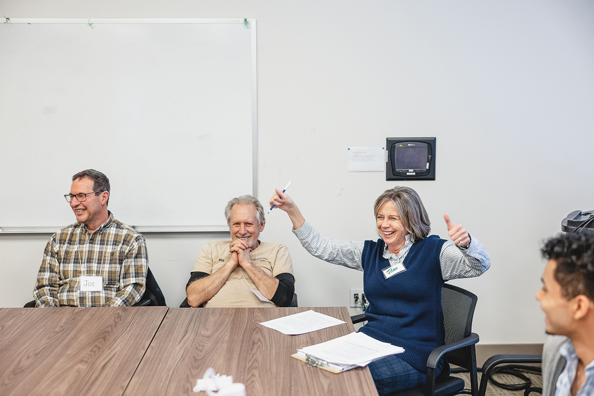 Four people sitting at a table, smiling and talking