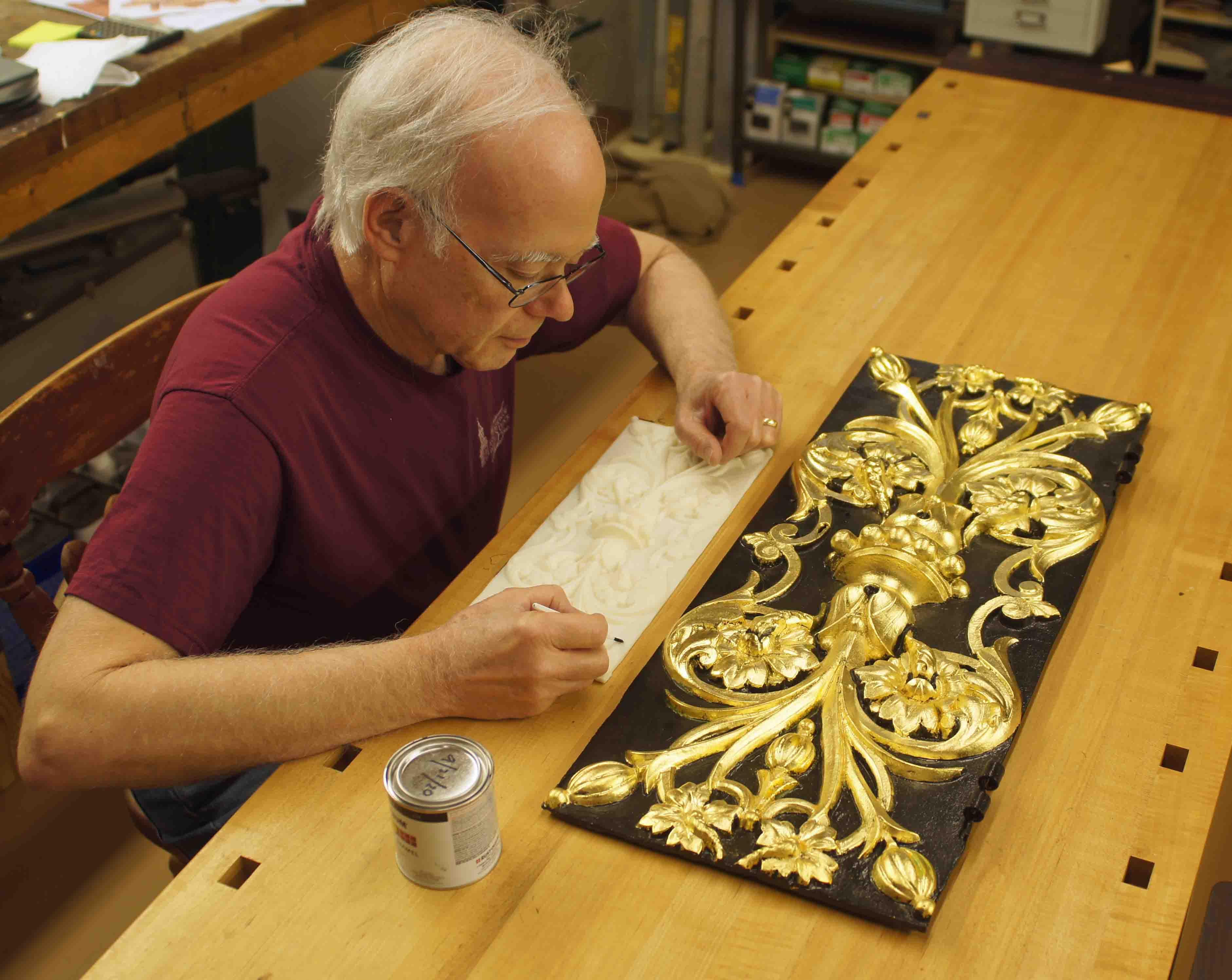 Frank Del Greco at a workbench, a replica street clock panel sits in front of him.