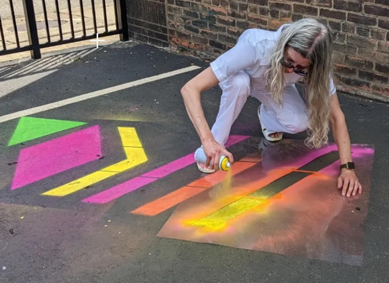 Artist Jen Craun demonstrates the use of a stencil with chalk spray paint.