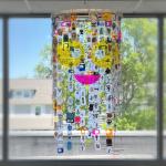 A mobile made of 200 shrinky-dink portraits with a plexiglass face.