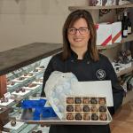 Ines Rehner of Sweet Designs Chocolatier holds a box of chocolates and chocolate mold prototypes in her shop.