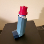 An inhaler with an additional red cap attached to the medicine canister