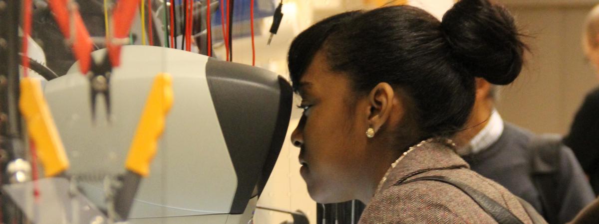 A young woman looks into a microscope.
