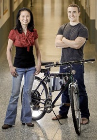 A woman and man standing next to a bike 