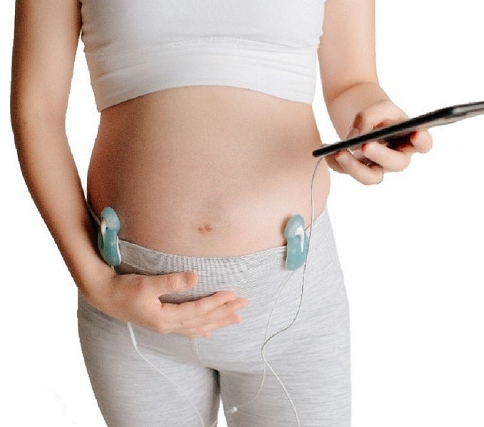 A pregnant woman wearing a device to hear her baby