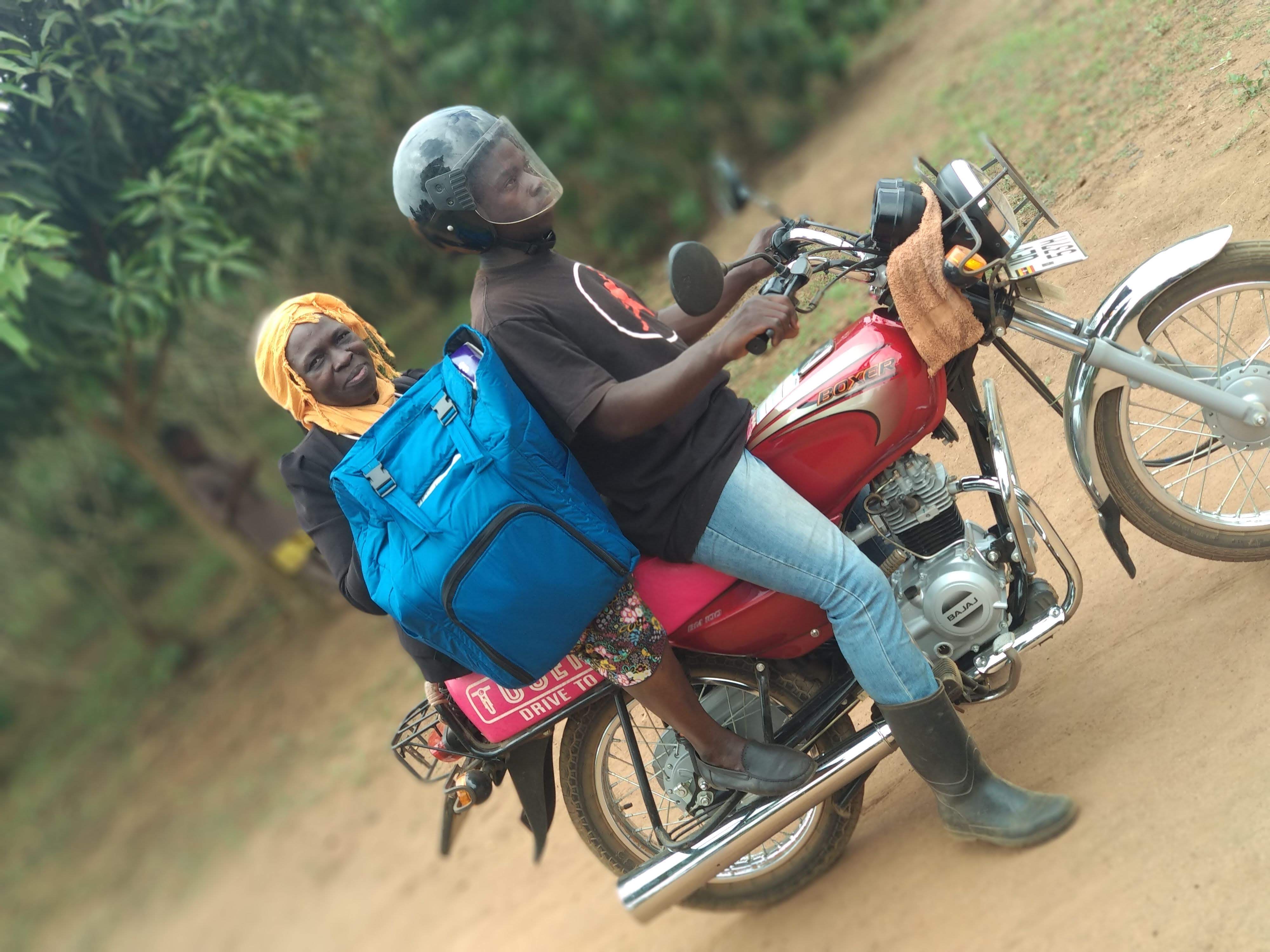 Two people on a motorcycle delivering vaccines in Uganda