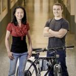 A woman and man standing next to a bike 