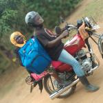 Two people on a motorcycle delivering vaccines in Uganda