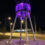 A water tower illuminated by purple light