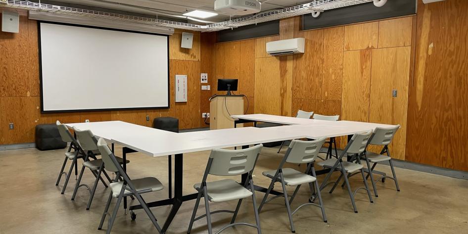 A presentation area with tables, chairs, a projector, and a podium