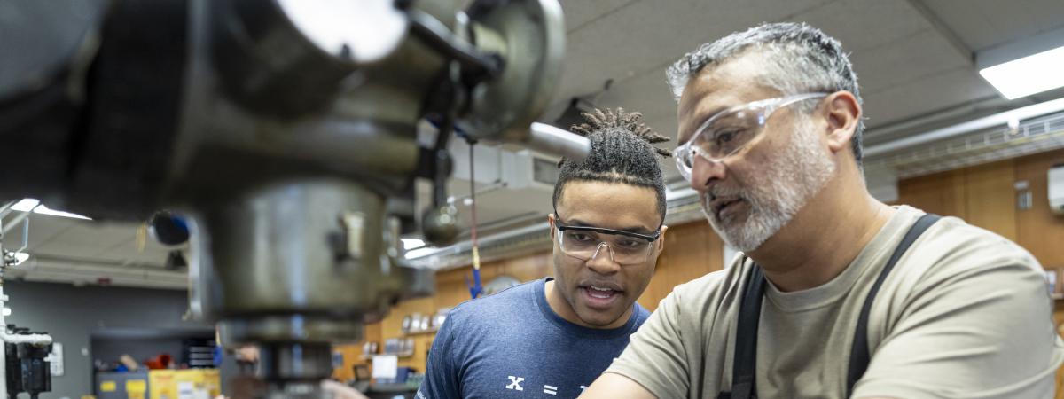 Fabrication Engineer working with student on metal machinery
